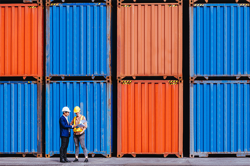 Panoramic of smart creative foreman and engineer woman control loading containers box from cargo freight ship for import export. Logistic, transportation, import and export concept