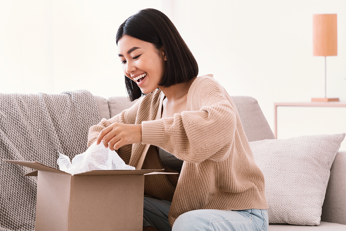 Happy asian lady unpacking parcel after online shopping